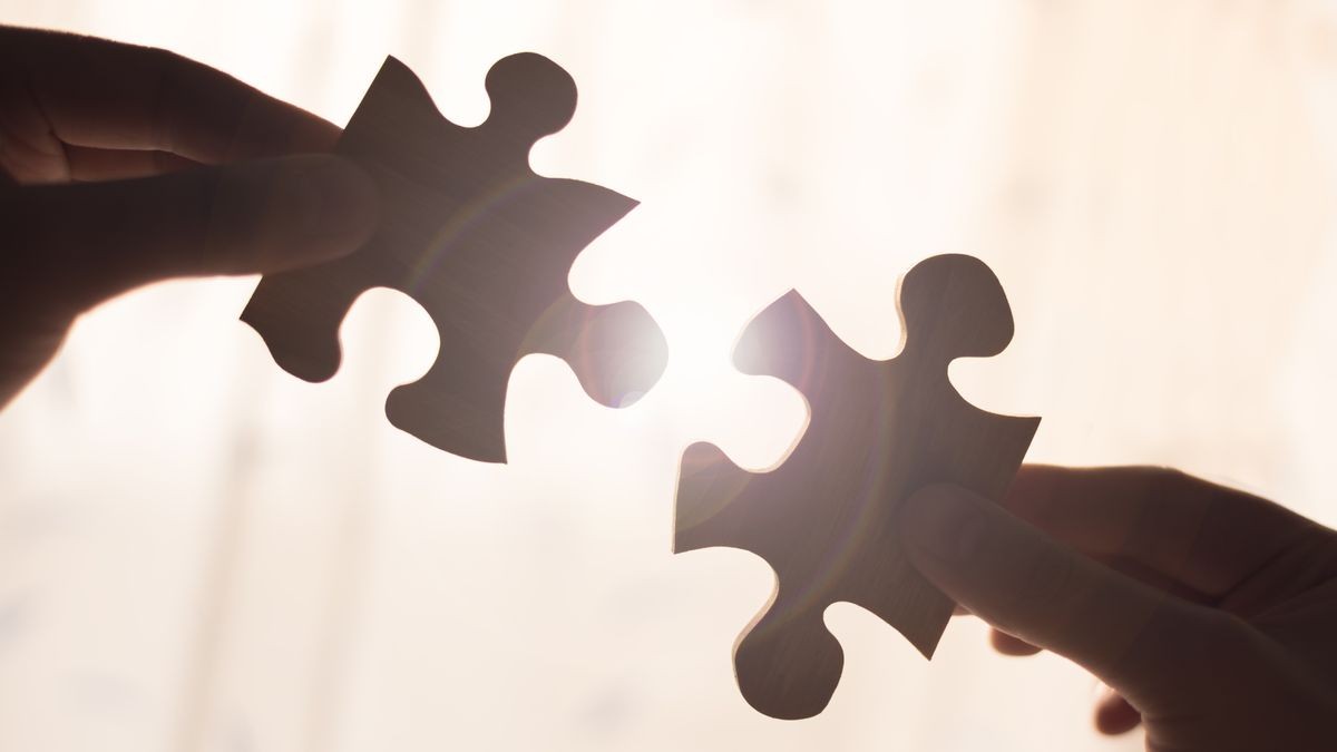 Two hands trying to connect couple wooden puzzle piece. Concept of association and connection, business strategy.
